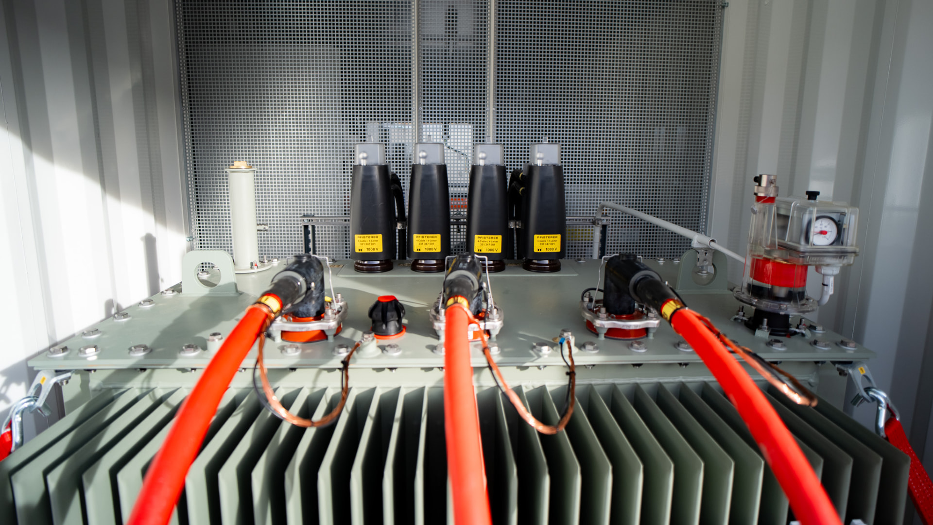 Detailansicht eines Transformators mit PFISTERER-Kabelanschlüssen und orangefarbenen Hochspannungskabeln